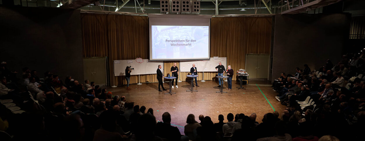 Publikum mit Podiumsdiskussion in der Mitte