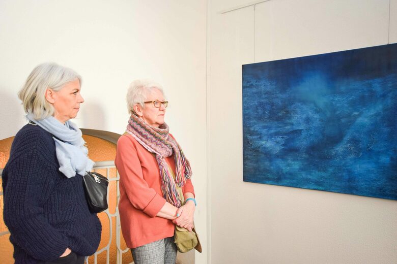 Die Künstlerinnen Birgit Feike und Agnes Fockenberg betrachten ein Gemälde der Ausstellung